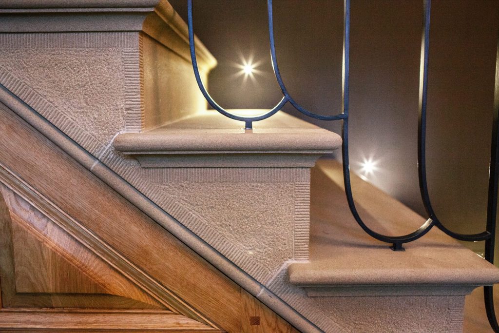 Carved stone staircase with metal handrail and Oak panelling