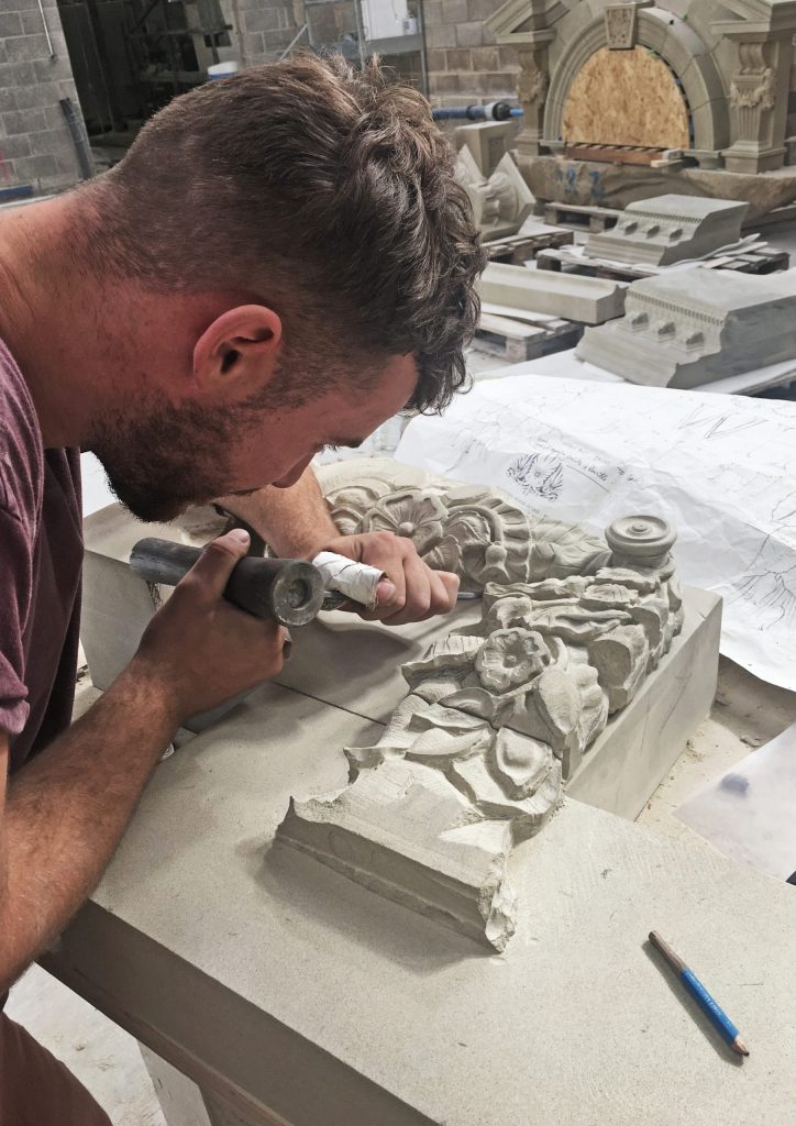 Stone mason carving ornate stone swag