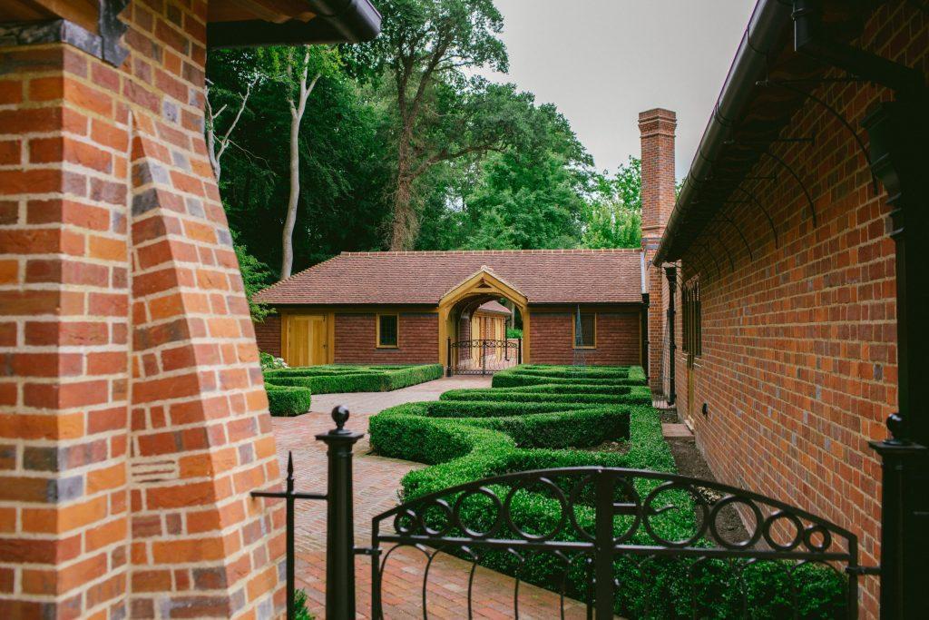 Formal kitchen garden design with bespoke metal gates and stables building in brick and oak