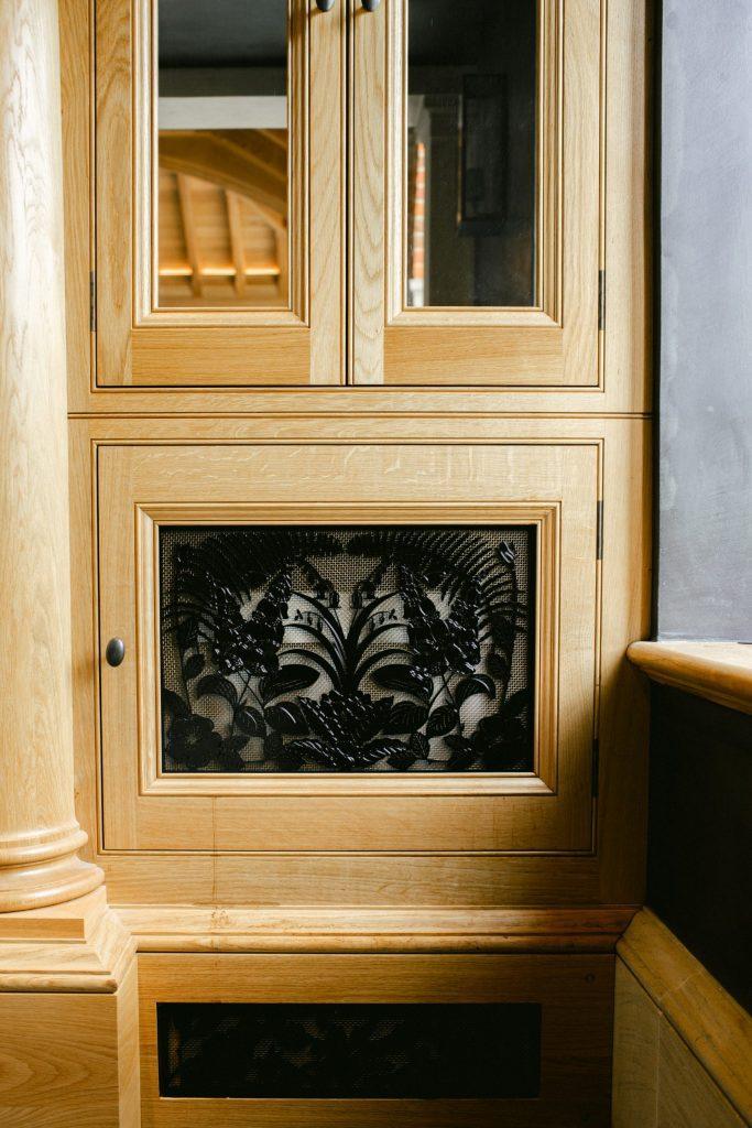 Black metal vent covers in bespoke Oak cabinet