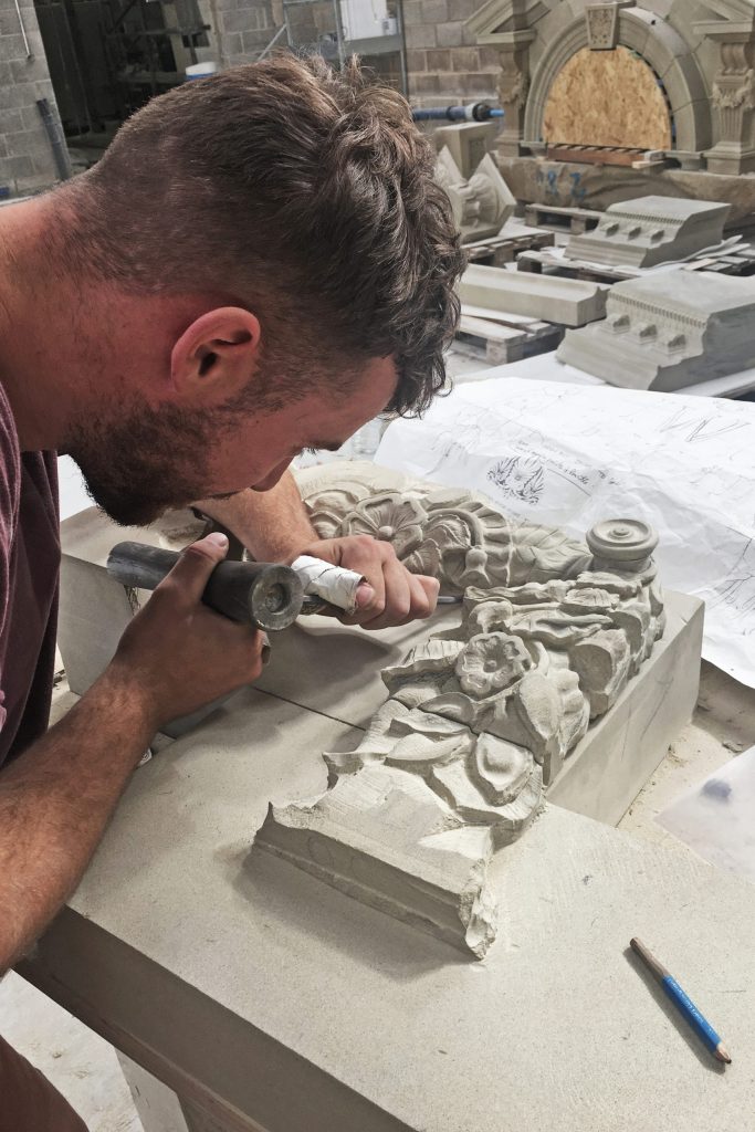 Intricate stone carving by mason in workshop