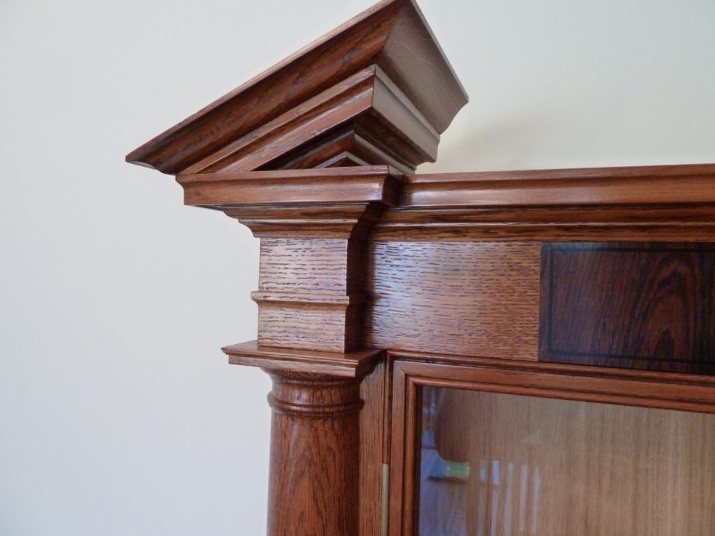 Broken pediment in Oak on classical war medal display cabinet