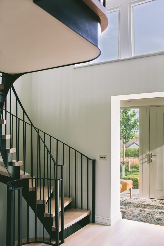 Double height light hallway with metal curved staircase