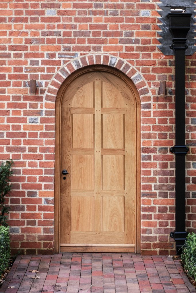 Oak panelled traditional door in brick arch