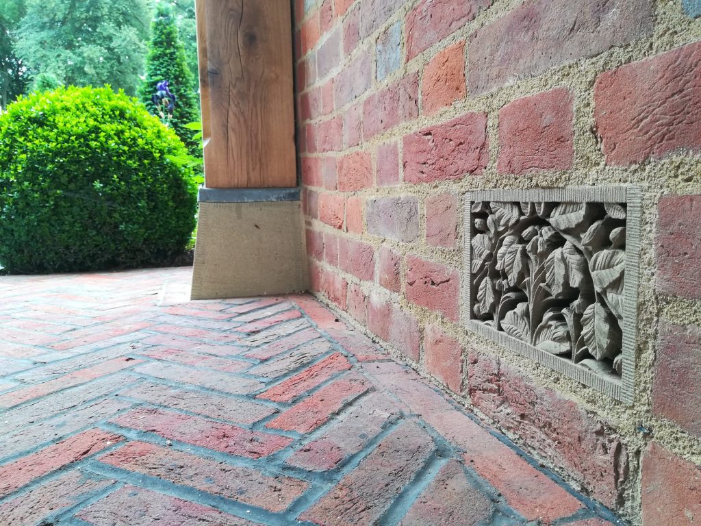 Carved stone air brick in brick wall Carved stone decorative air brick in country house