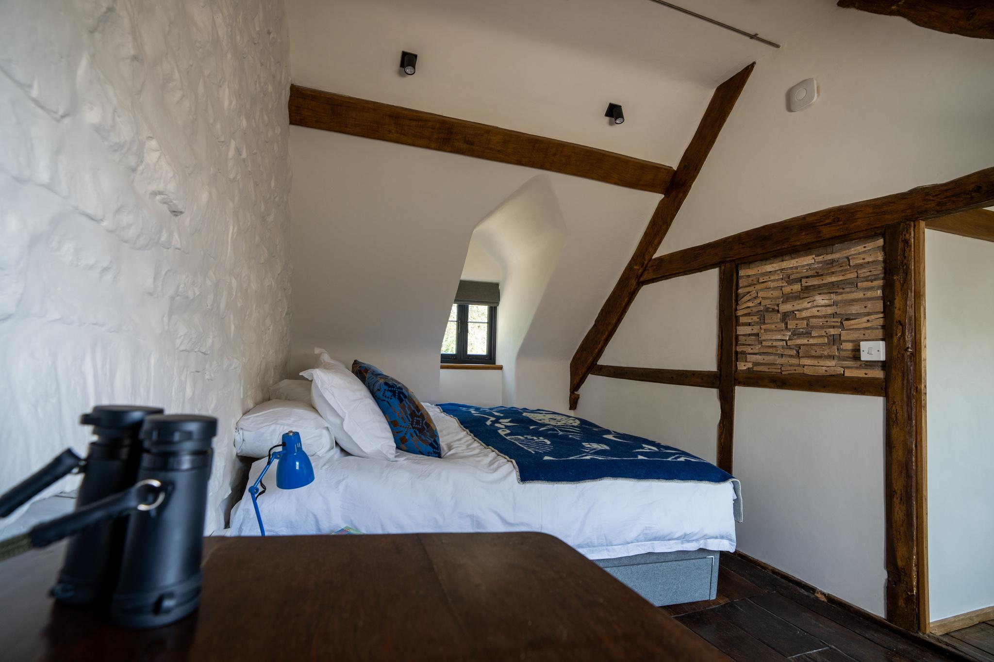 A restored bedroom in the traditional Welsh longhouse with exposed original lath and plaster.