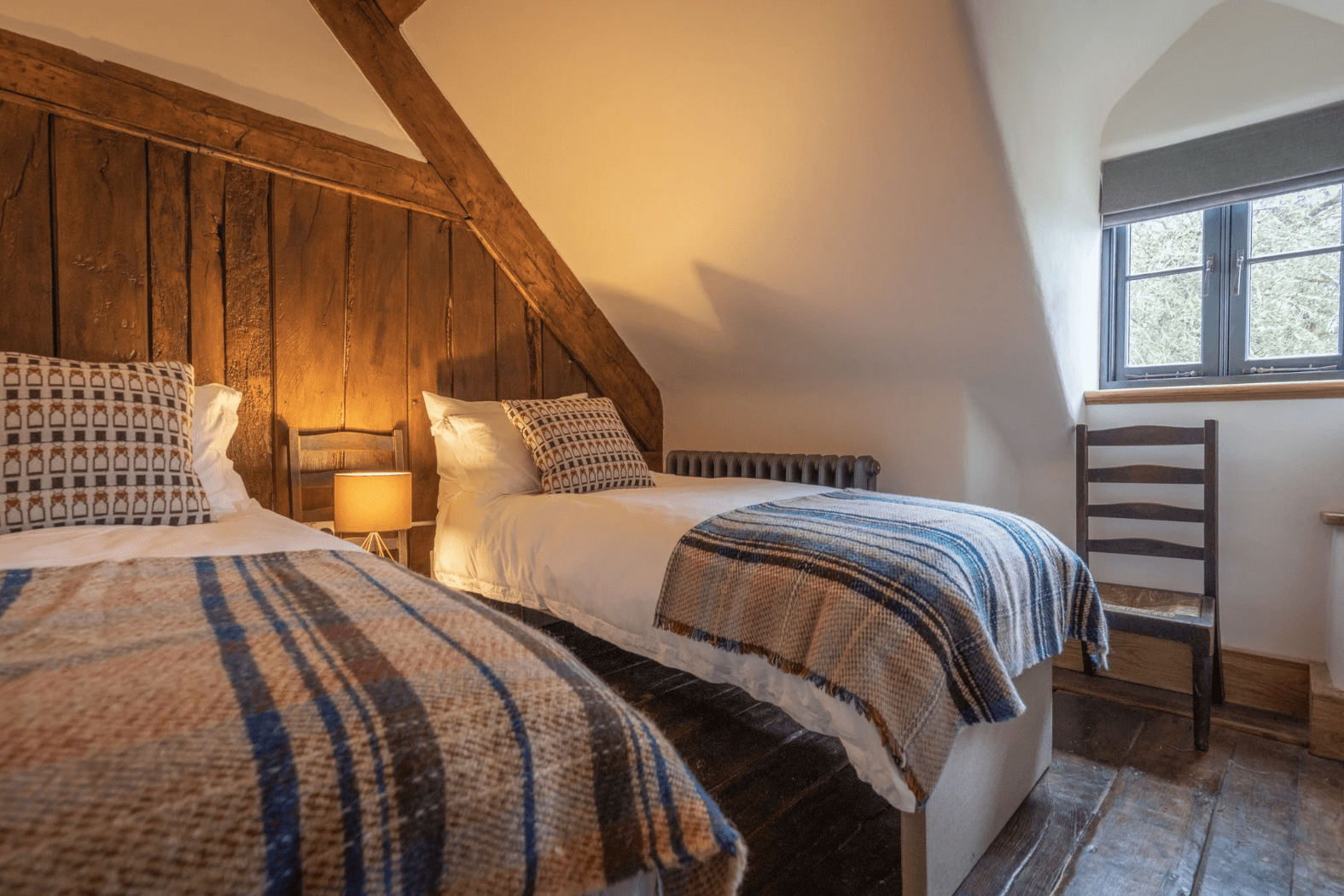 A restored historic Welsh farmhouse bedroom with exposed original features and floor.